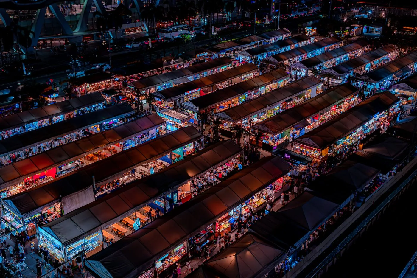 Aerial view of a colorful Bangkok night market filled with stalls and visitors